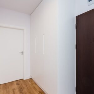 Распашной шкаф из белого крашеного МДФ с интегрированными ручками в прихожую комнату возле входной двери