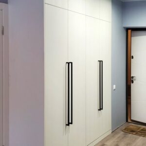 Корпусный белый шкаф от пола до потолка для прихожей с длинными тонкими контрастными черными ручками