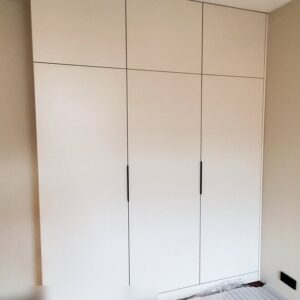 Трехдверный распашной шкаф бежевого цвета из МДФ крашеного в спальню с небольшими черными торцевыми ручками