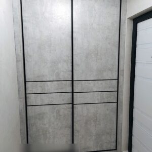 Серый шкаф-купе с текстурой светлого бетона в черном профиле в прихожую возле входной двери