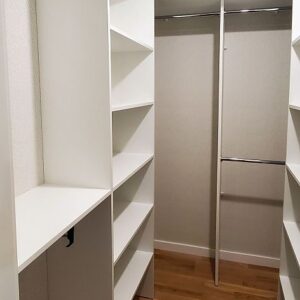 Белая мебель в выделенную гардеробную комнату с выдвижными вешалками для узких зон хранения и штангами для более глубоких