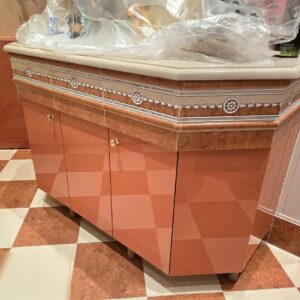 Красно-оранжевая напольная тумба с золотыми ручками и опорами под массивную столешницу из искусственного камня с отделкой плиткой