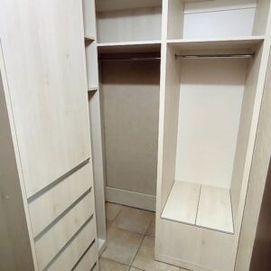 Небольшая гардеробная комната со шкафчиками, вешалками и полками в отделке под светлое дерево