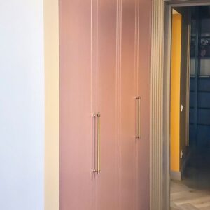 Шкаф со складными створками с доводчиком из крашеного МДФ пыльно-розового цвета с золотыми ручками